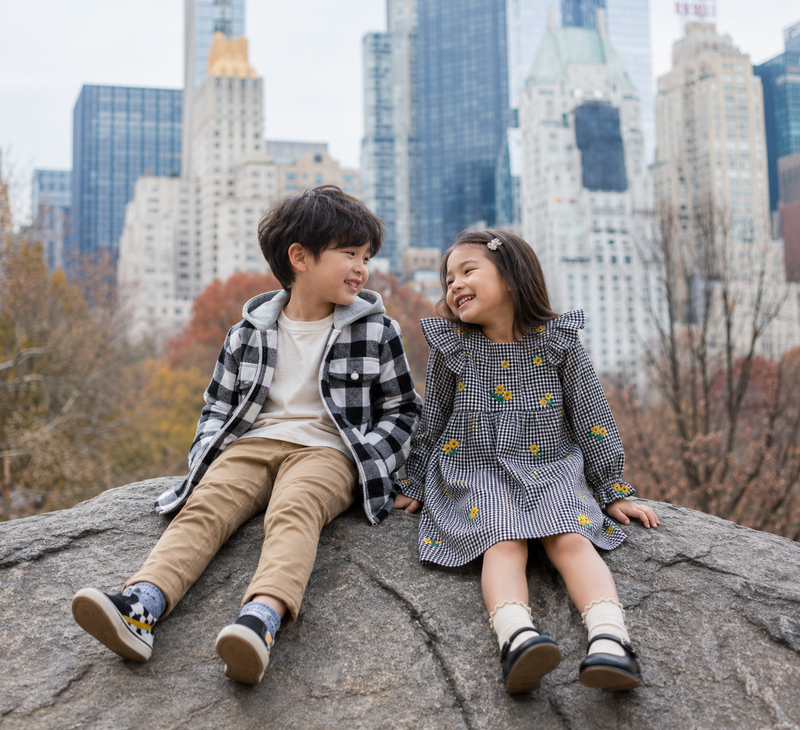 Girl in black and white check floral dress laughs with her brother in Central Park, cute girls fall outfits