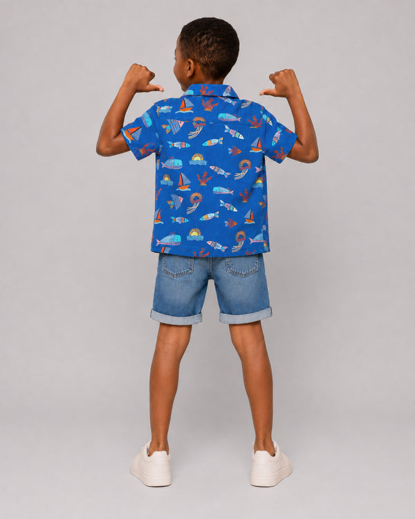 Boys ocean themed shirt in blue, sailboat and fish print, back view on model