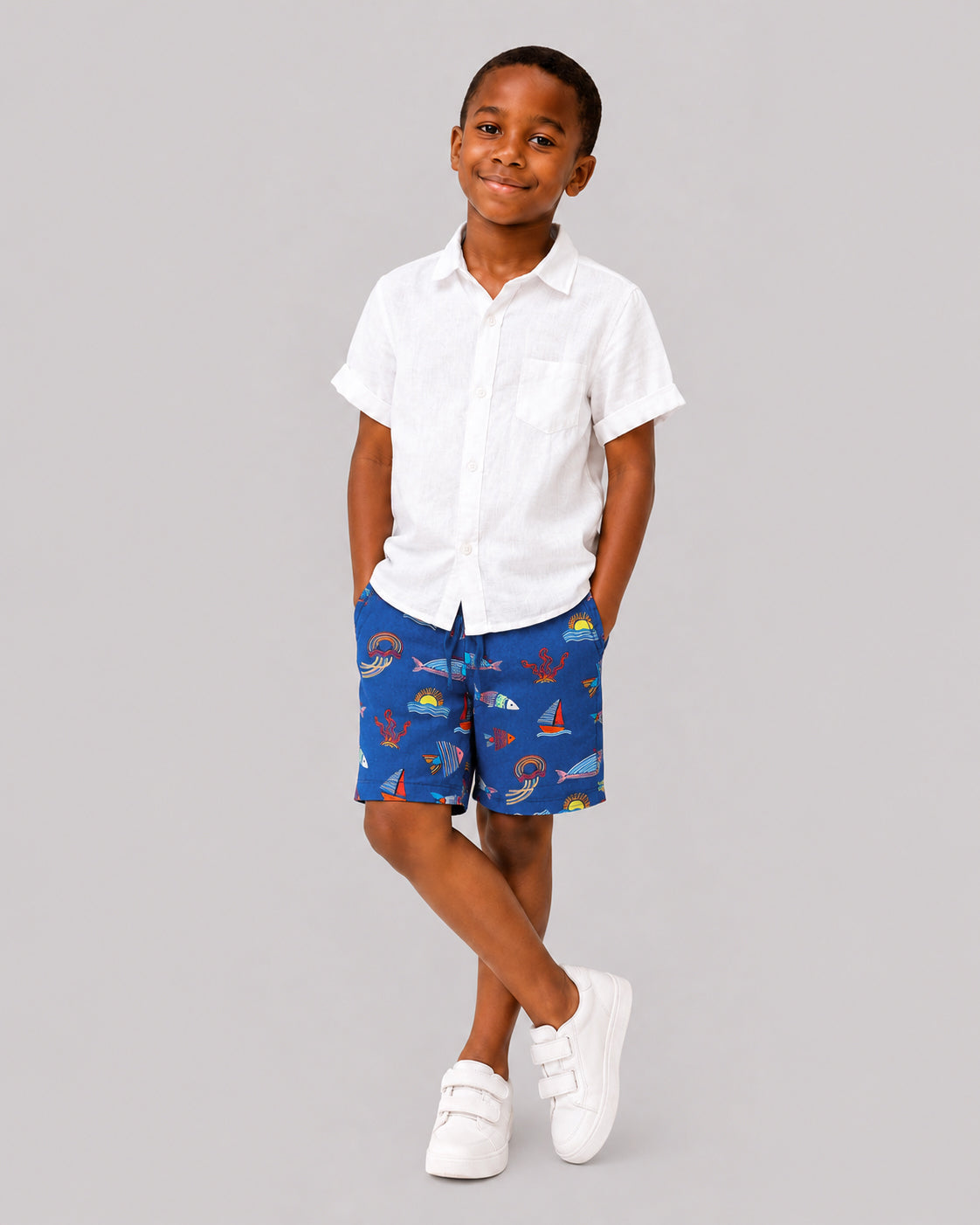 Boys ocean themed shorts in blue, sailboat and fish print, on model