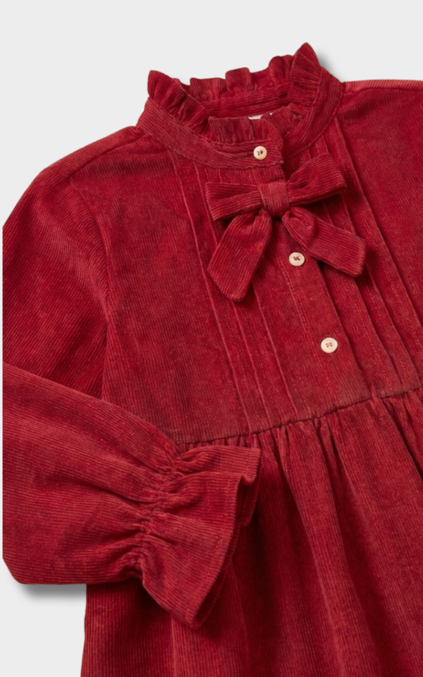 Closeup of the velvet bow, pintucks, and buttons on a red corduroy dress, detailed girls clothing
