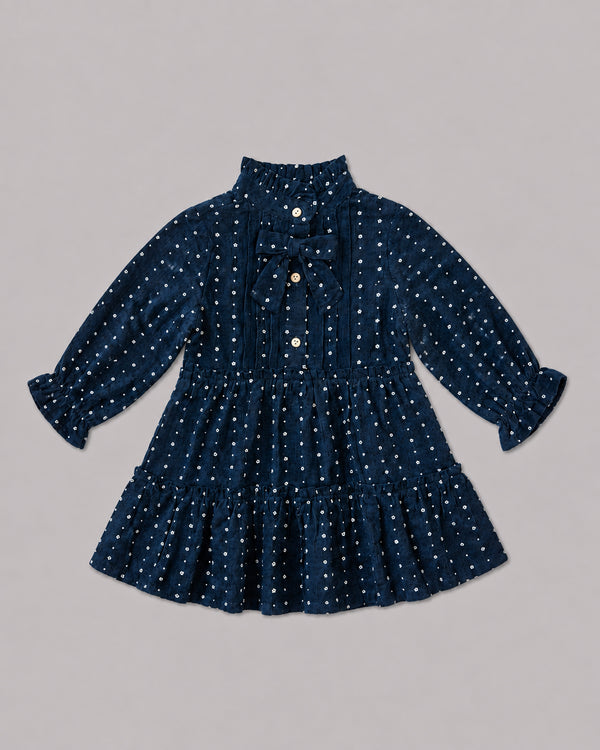 Flat lay of navy dotted dress with pintuck front and velvet bow tie, a pretty smock dress