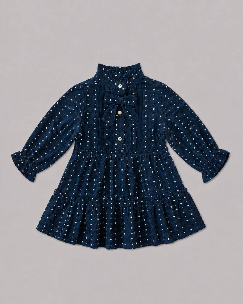 Flat lay of navy dotted dress with pintuck front and velvet bow tie, a pretty smock dress