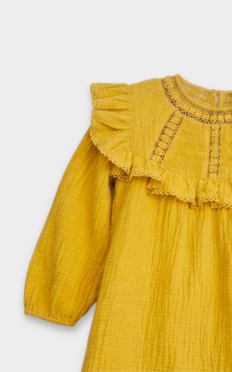 Closeup of crochet lace yoke and ruffle trim on mustard yellow dress, detailed girl clothes