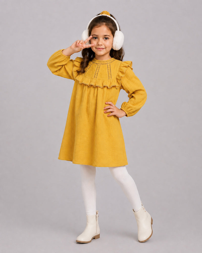 Smiling girl in mustard yellow lace dress making a peace sign, a relaxed smock dress silhouette