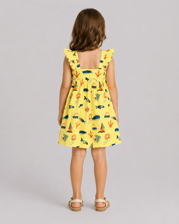 Girls ocean themed dress in yellow, sailboat and fish print, back view on model
