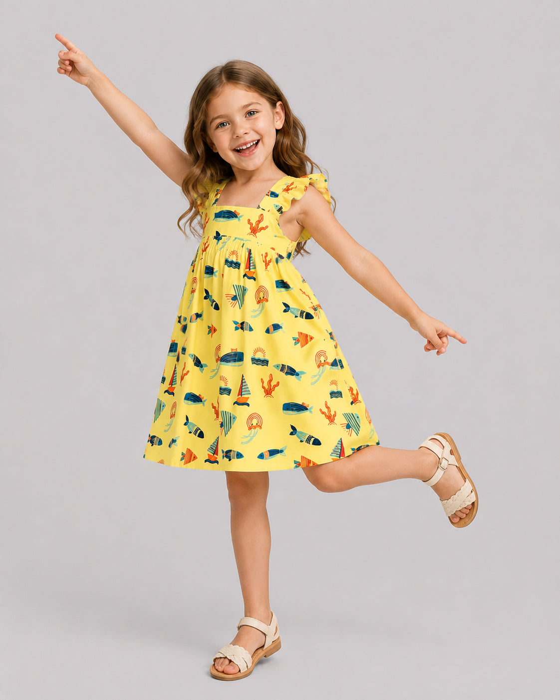 Girls ocean themed dress in yellow, sailboat and fish print, on model dancing pose