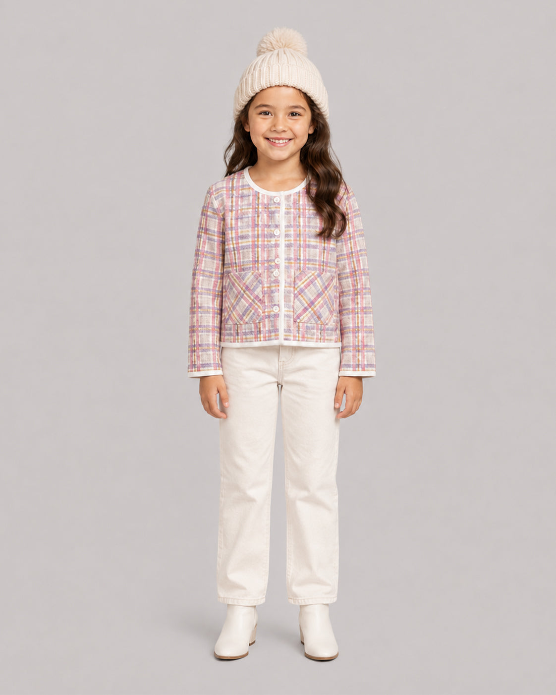 Smiling girl in pink tweed plaid jacket, cream jeans, and pom hat, a sweet toddler coat