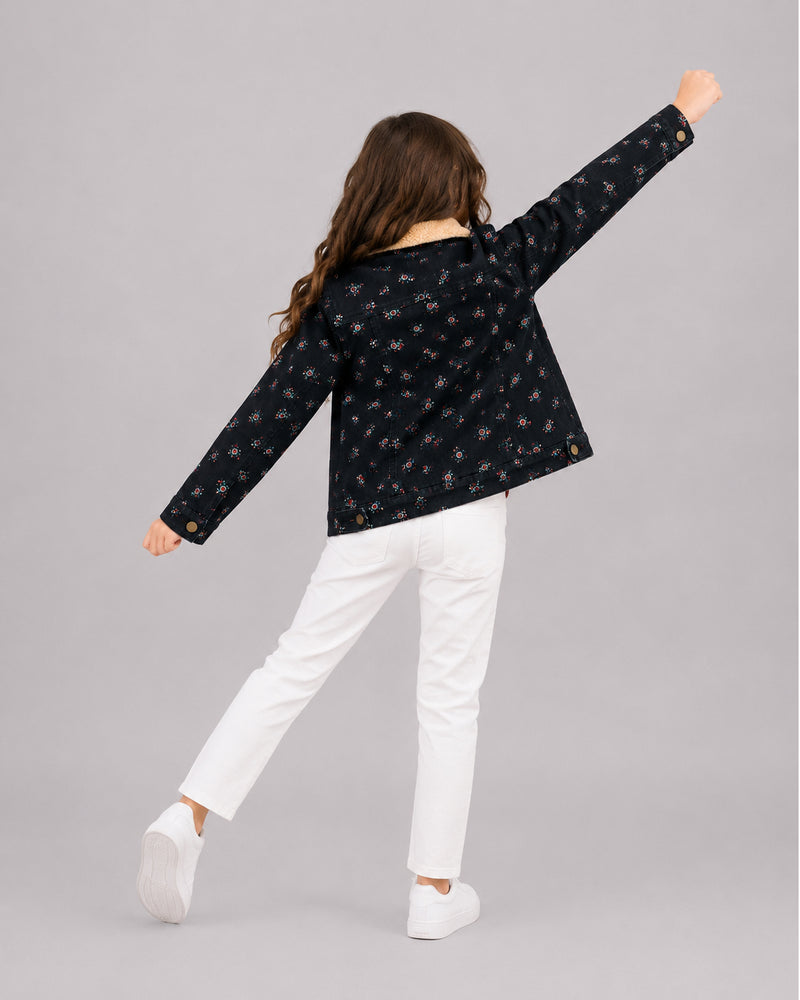 Girl mid-motion in navy floral jacket with sherpa collar, playful girls coats from behind