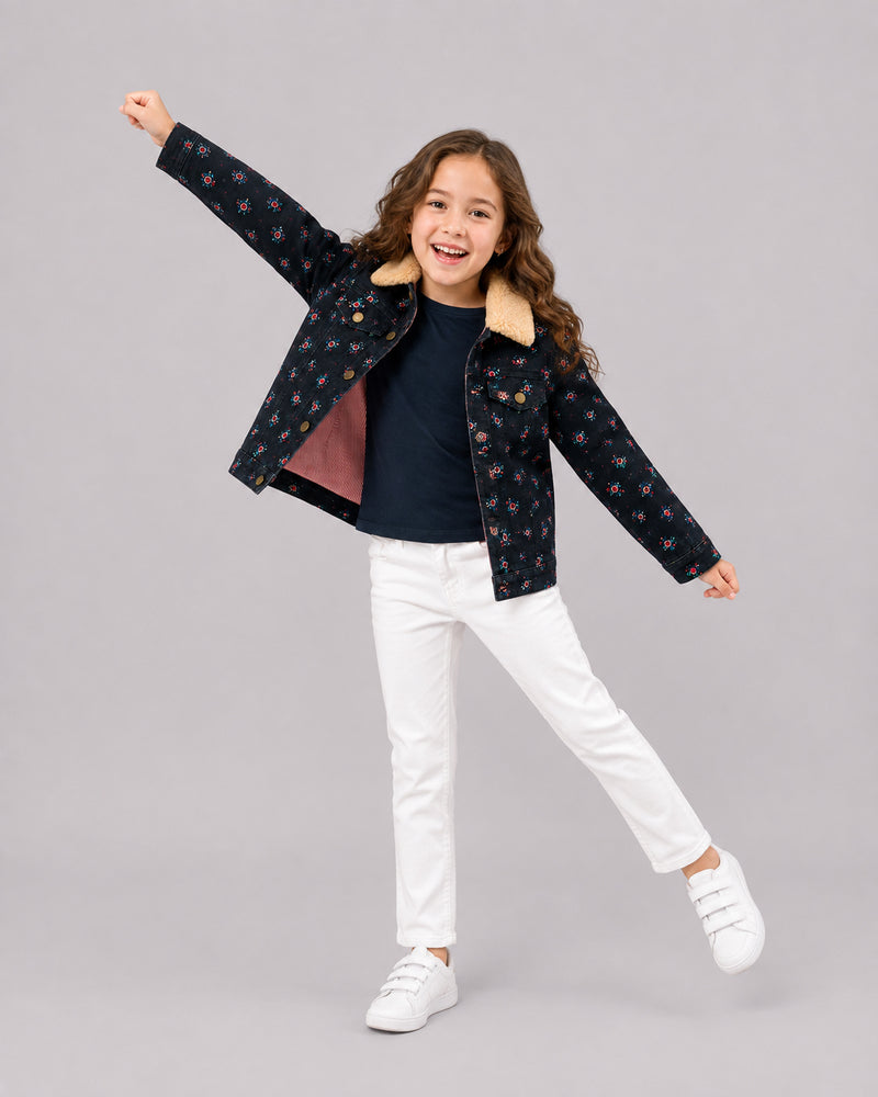 Smiling girl jumping in navy floral sherpa-collar jacket and white jeans, a cute toddler coat