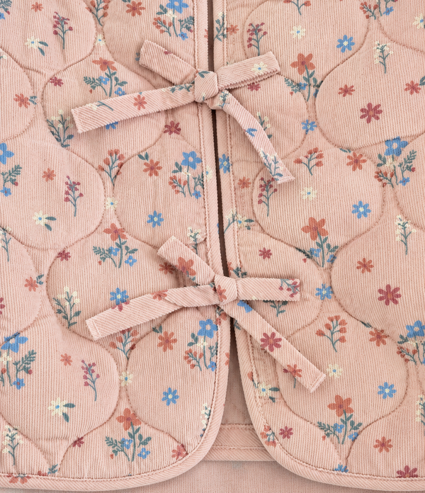 Closeup of corduroy bow ties on dusty pink floral quilted jacket, a sweet toddler coat detail