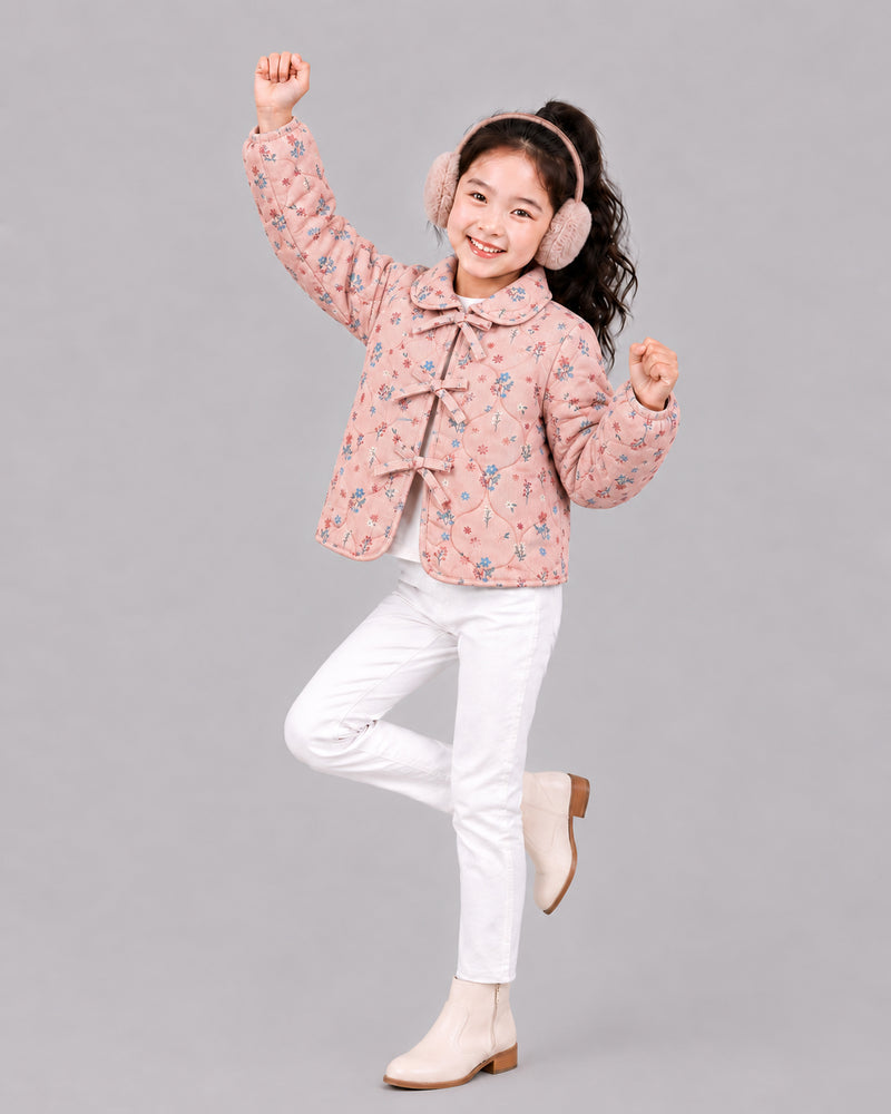 Girl dances in dusty pink floral jacket, ear muffs, and white jeans, a playful pick from coats for kids