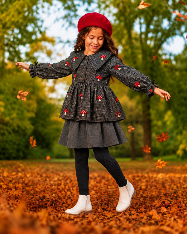 Girl twirls in autumn leaves wearing grey houndstooth mushroom top, fall dresses for girls look